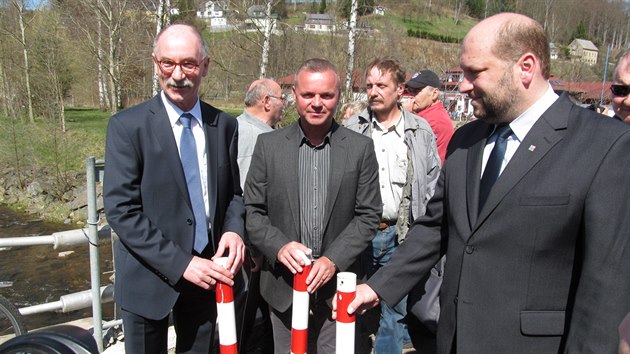 Starosta Olbernhau Steffen Laub, starosta Brandova Ji Mooz a krajsk radn Jaroslav Komnek pi oteven hranice symbolicky odmontovali barevn hranin kly. (15. dubna 2015)