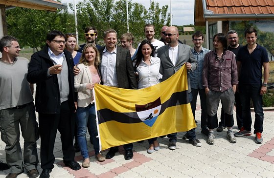 Vít Jedlika (uprosted v saku bez brýlí) s píznivci a vlajkou státu Liberland...