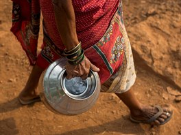 Sakhri, second wife of Sakharam Bhagat, carries an empty metal pitcher as she...