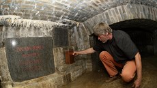 Restaurátor Andrej embera ukládá schránku s listinami a pedmty v podzemí...