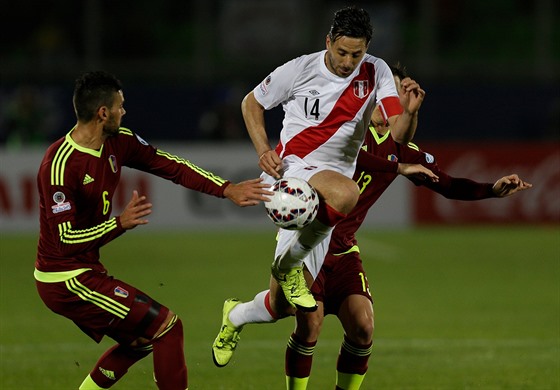 Claudio Pizarro se snaí odpoutat od bránících hrá Venezuely. Vlevo je...