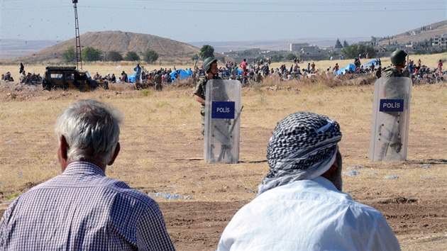 Turet vojci ste hranice se Sri, v pozad jsou lid z Kobani, kte chtj do Turecka (26. ervna 2015).