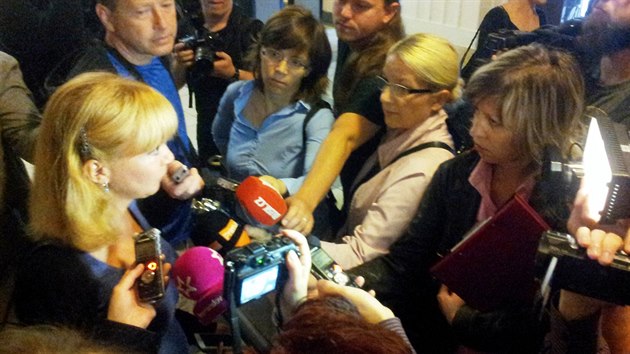 Novináři zpovídají před začátkem líčení zmocněnkyni poškozené rodiny Kláru Long Slámovou.