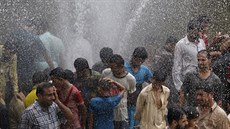 Lidé se chladí u prasklého vodovodu v Karáí. (25. 6. 2015)