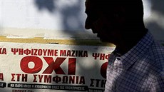 Mu prochází kolem plakát s nápisy Masivn volíme NE dohod v centru Atén....