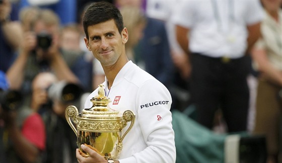 Novak Djokovi hrd pózuje s trofejí pro vítze Wimbledonu.