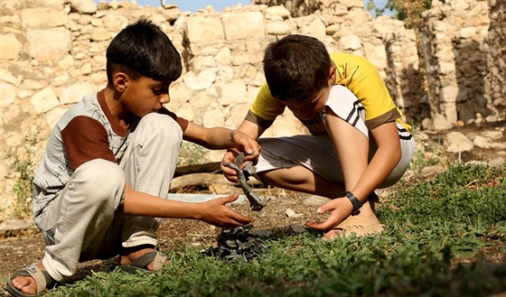Chlapci si hrají s kousky kovu, které nali u kráteru, který vznikl po náletu...