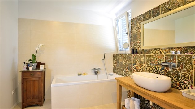 Koupelnu v jednoduchm a strohm stylu oiv vrazn obklady s exotickm dekorem v zemitch tnech.