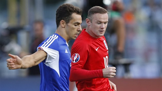 Anglick fotbalista Wayne Rooney (v ervenm) se petahuje o m s Cristianem Brollim ze San Marina v kvalifikanm duelu o Euro 2016.