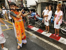 People look as a devotee of the Chinese Bang Neow shrine with a rifle pierced...