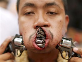 A devotee of the Chinese Bang Neow shrine walks with guns pierced through his...