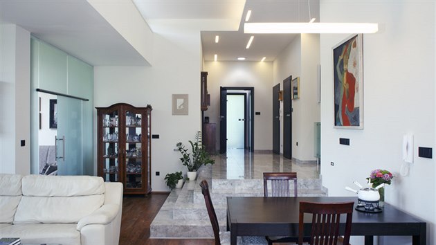 Pracovna umístěná za stěnou z matného skla (vlevo) s posuvnými dveřmi může a nemusí být přímou součástí dění v obývacím pokoji.