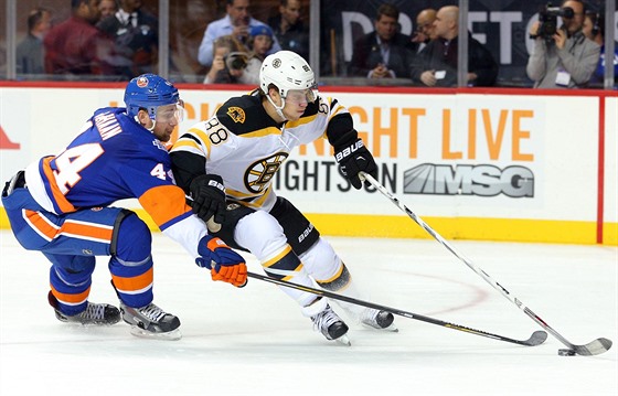 Calvin de Haan z NY Islanders se snaí vypíchnout puk, který má pod kontrolou...