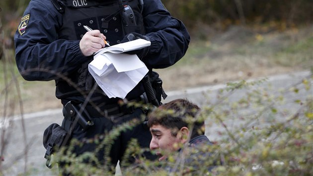 Policista zasahuje u rozmky mezi migranty ekajcmi na registraci ve Slovinsku (28. jna 2015)