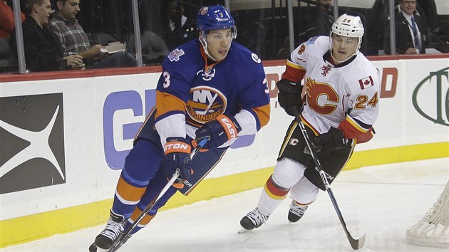 Ji Hudler z Calgary sth soupee, Travis Hamonic z  New York Islanders vyv puk.