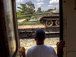 KUBA. Na této fotce se mu dívá na odstavený nákladní vlak peváející tank v...