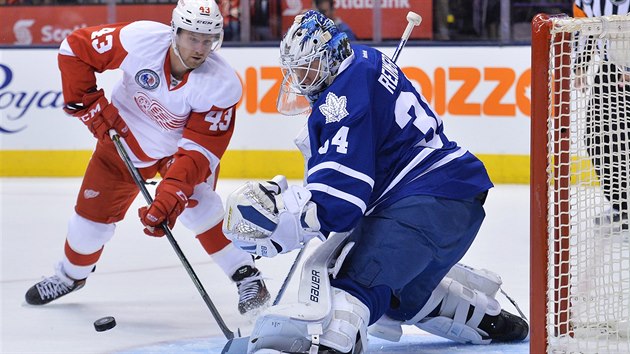 Glman Toronta James Reimer zasahuje, do ance se dostal Darren Helm z Detroitu.