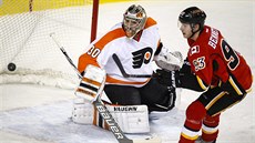 Michal Neuvirth v brance Philadelphie a Sam Bennett  z Calgary sledují vyraený...