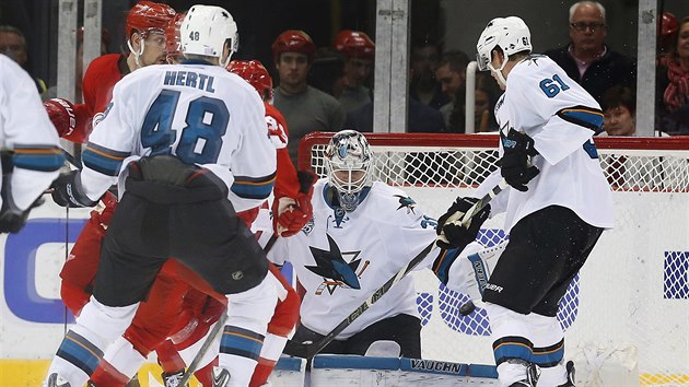 Tom Hertl ze San Jose sleduje, jak jeho brank Martin Jones inkasuje po stele Teemu Pulkkinena z Detroitu.