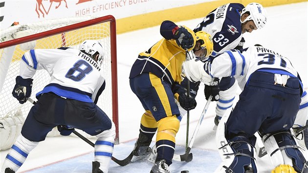 Glman Ondej Pavelec z Winnipegu se sna ve spoluprci se spoluhri Jacobem Troubou (vlevo) a Dustinem Byfuglienem eliminovat anci  Gabriela Bourquea z Nashvillu.