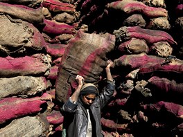 ZÁSOBY NA ZIMU. Afghánský pracovník nosí pytle s uhlím na trhu v Kábulu. Ceny...