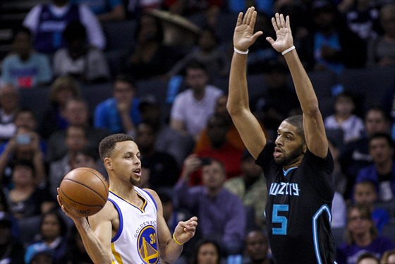 Steph Curry (vlevo) z Golden State hledá spoluhráe, Nicolas Batum z Charlotte...