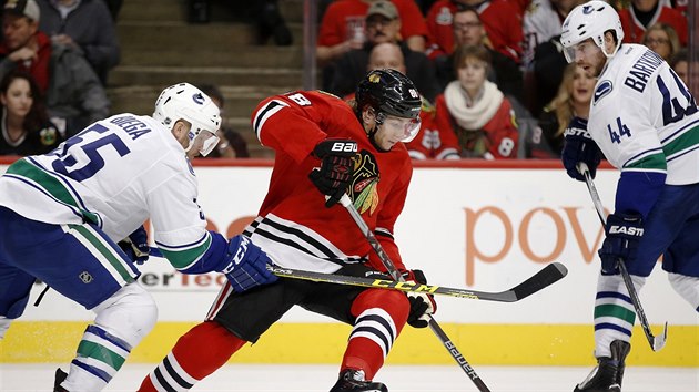 Patrick Kane z Chicaga (v ervenm) se sna projt mezi hokejisty Vancouveru.