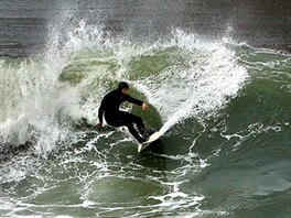 POD ZLATOU BRÁNOU. Surfa brázdí rozbouenou hladinu pod mostem Golden Gate v...