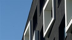 Fasáda budovy je minimalisticky erná, s bílými okenními rámy.