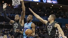 Kemba Walker (uprosted) z Charlotte atakuje ko Milwaukee kolem Grega Monroa...