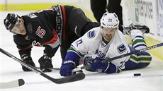 Daniel Sedin z Vancouveru (vpravo) a Andrej Nestrail z Caroliny v souboji o puk