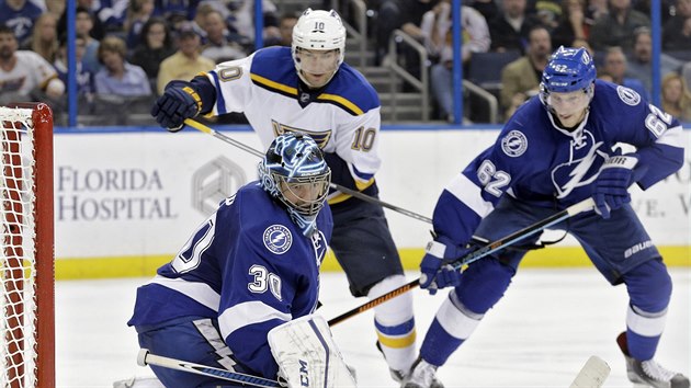 Brank Tampy Bay Ben Bishop kontroluje puk, pomoci se mu sna spoluhr Andrej ustr (vpravo), kter hldkuje u Scottieho Upshalla ze St. Louis.