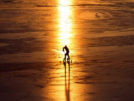 HOKEJISTA. Zbytky svtla ped západem slunce vyuívá hrá hokeje, který...