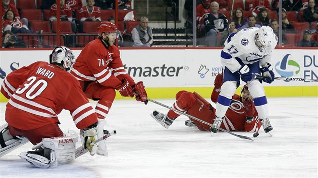 Ped brankem Caroliny Camem Wardem je ivo. Puk odehrv Jaccob Slavin, na led skonil  jeho spoluhr Andrej Nestrail a v pedklonu se sna  Alex Killorn z Tampy.