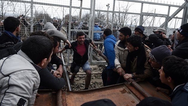 Uprchlci se sna prorazit plot provizornm beranidlem 
(29. nora 2016).