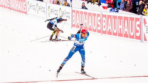 V CLI. Michal lesingr finiuje ve sprintu na mistrovstv svta v biatlonu v Oslu, za nm se sbr upadnuv Nmec Schempp.