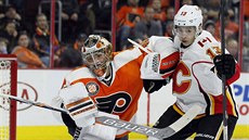 Branká Michal Neuvirth z Philadelphie v souboji s Johnnym Gaudreauem z Calgary.