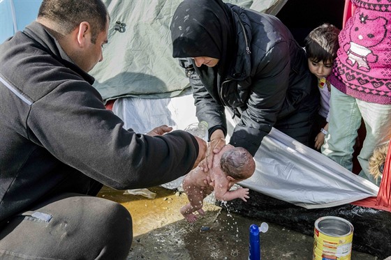 Uprchlíci v táboe Idomeni omývají novorozence (6. bezna 2016)