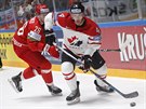 Kanadský hokejista Taylor Hall (vpravo) ujídí Nikitovi Ustinnkovi z Bloruska.