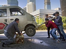 VÝPOMOC. Kolemjdoucí pomáhají nadzvednout mini dodávku, která uvízla na jedné z...