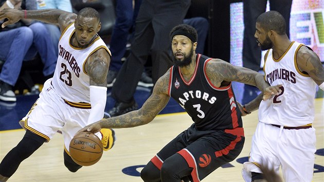 POD TLAKEM.  James Johnson z Toronta se sna udret m mezi dvojic Kyrie Irving (vpravo) a LeBron James z Clevelandu.