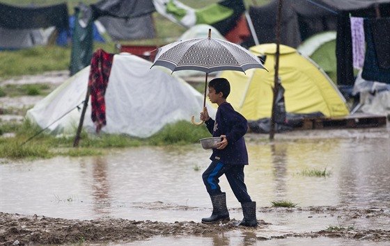 Chlapec si nese jídlo pes zatopené ásti uprchlického tábora v Idomeni u...