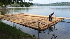 Muž vyrábí vor, který povozí na přehradě návštěvníky Muž vyrábí vor, který povozí na přehradě návštěvníky