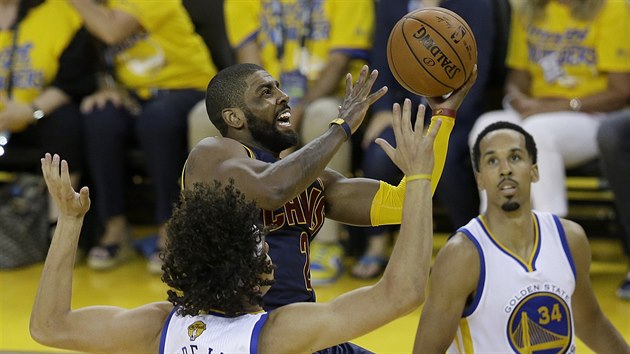 Kyrie Irving (v tmavm) z Clevelandu se pokou zakonit v souboji s Andersonem Varejaem z Golden State. Pihl Shaun Livingston.