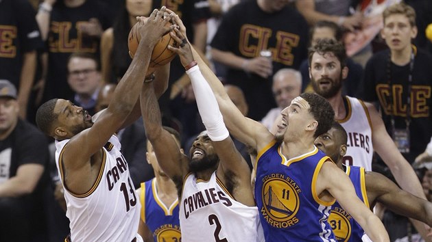 Tristan Thompson (13) a Kyrie Irving (2) z Clevelandu bojuj na doskoku s Klayem Thompsonem (11) z Golden State.