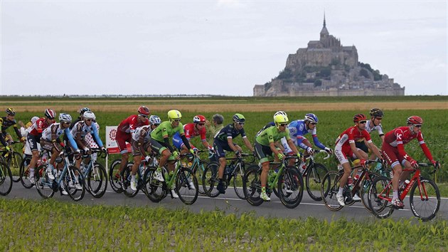 Cyklist v vodn etap Tour de France projdj okolo plivovho ostrovu Mont Saint-Michel.