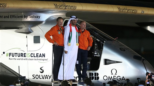 Piloti Andre Borschberg a Bertrand Piccard pzuj se Sultan Ahmedem Al Jaber u pilotn kabiny letounu Solar Impulse 2 po spnm obletu zemkoule 26. 7. 2016 v Ab Zab.