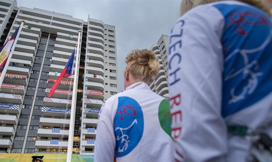 etí sportovci sledují slavnostní vyvení státní vlajky v olympijské vesnici.