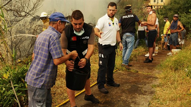 Civilist a policist ve Funchalu pomhaj hasit por alespo kbly s vodou (10. sprna 2016).