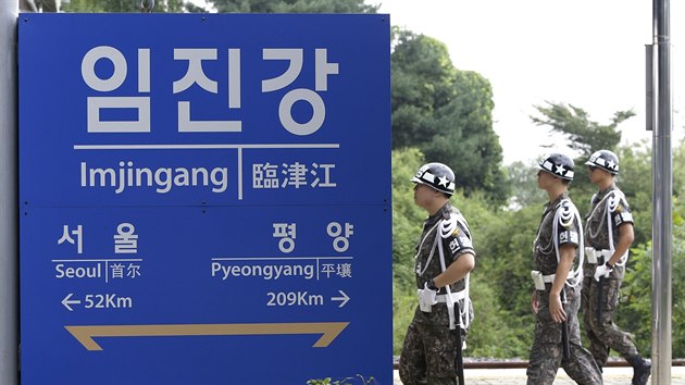 Jihokorejt vojci prochzej kolem cedule, oznaujc vzdlenost Soulu a Pchjongjangu od hranin stanice (11. z 2016)